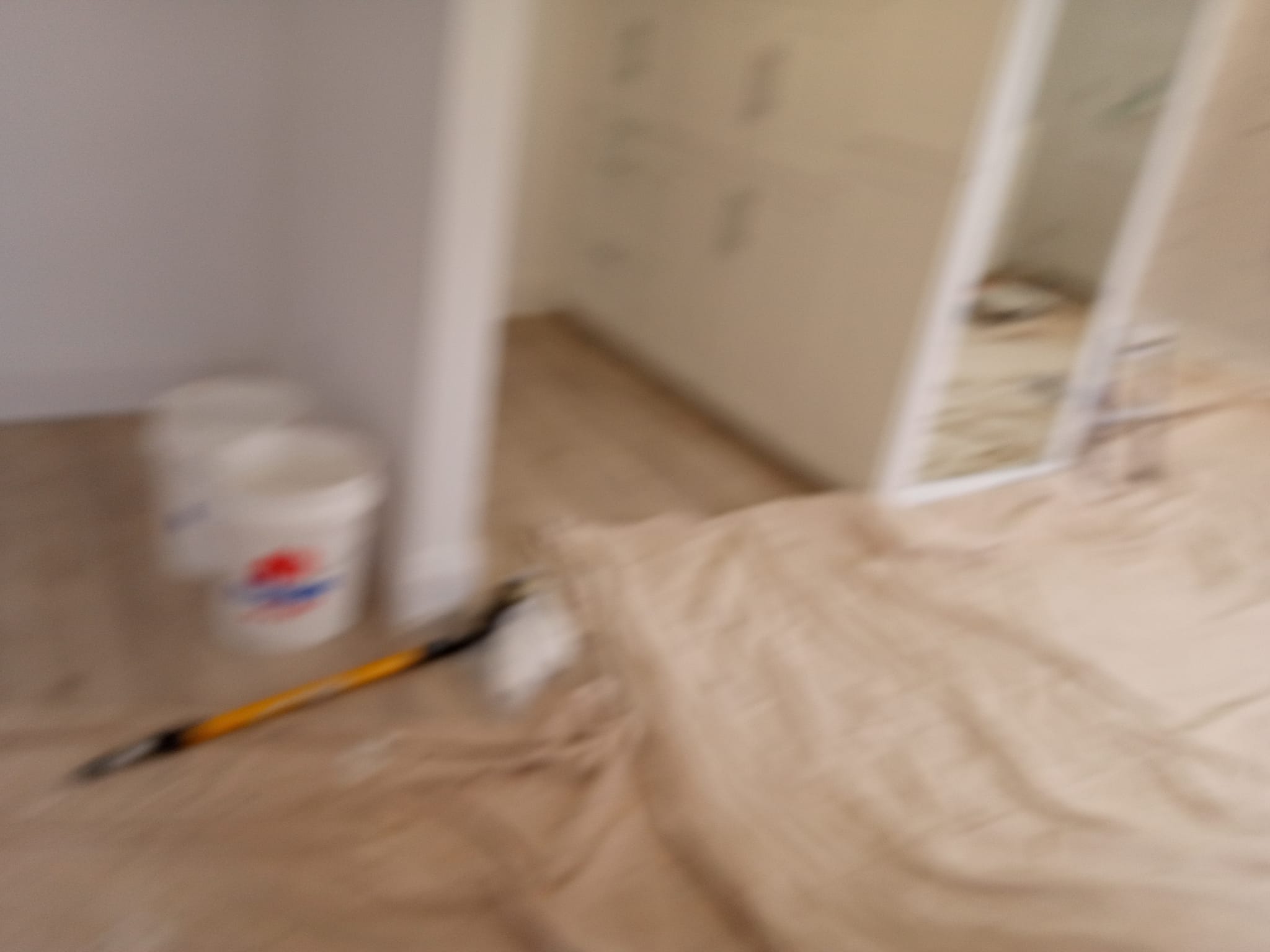 Painting tools and drop cloth on hardwood floor